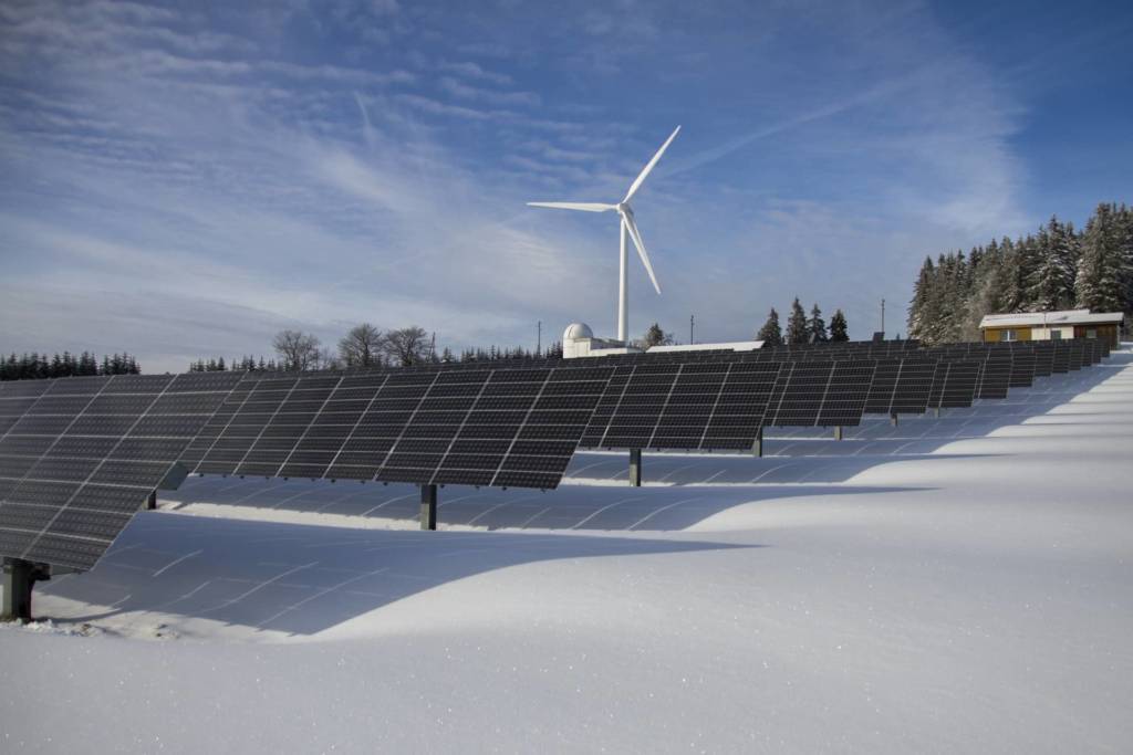 Photo of solar array with wind turbine in background